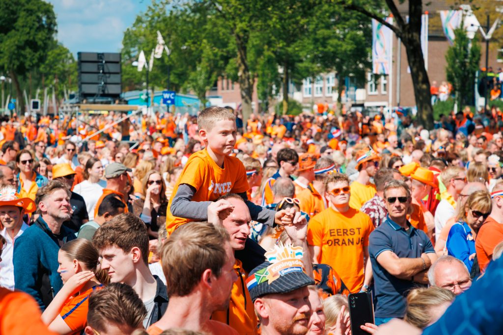 Publiek in oranje kleding kijkt naar optreden