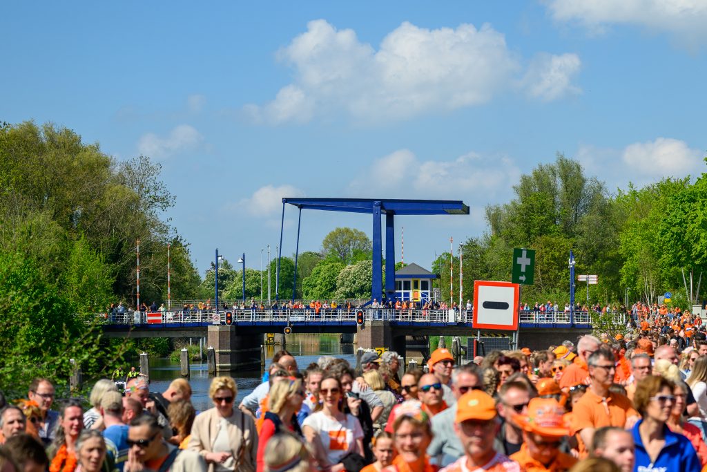 Blik op de fietsbrug met veel oranje publiek erop en ervoor
