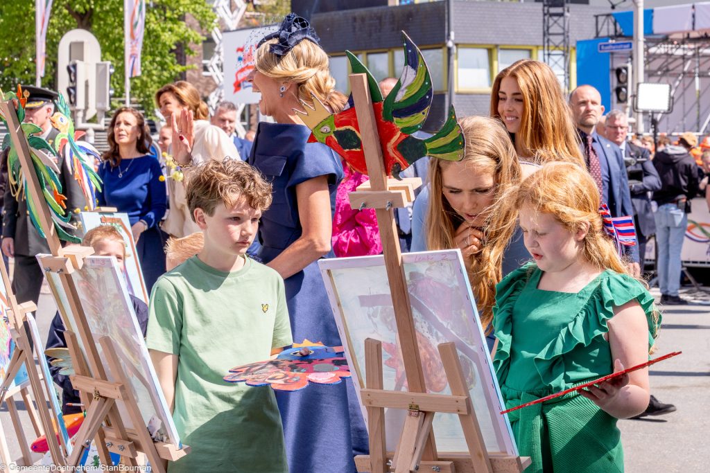 De koninklijke familie bekijkt de kunstwerken van kleine schilders bij de Koningspoort
