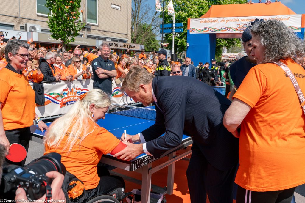 Koning Willem-Alexander zet handtekening op gipsen arm van lid paratafeltennisteam