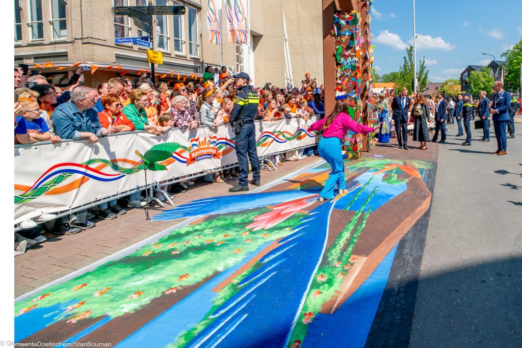 De koninklijke familie kijkt naar de grondschildering onder de Koningspoort